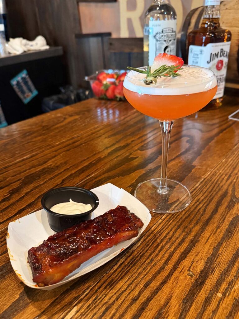 a wooden table topped with two drinks and a plate of food