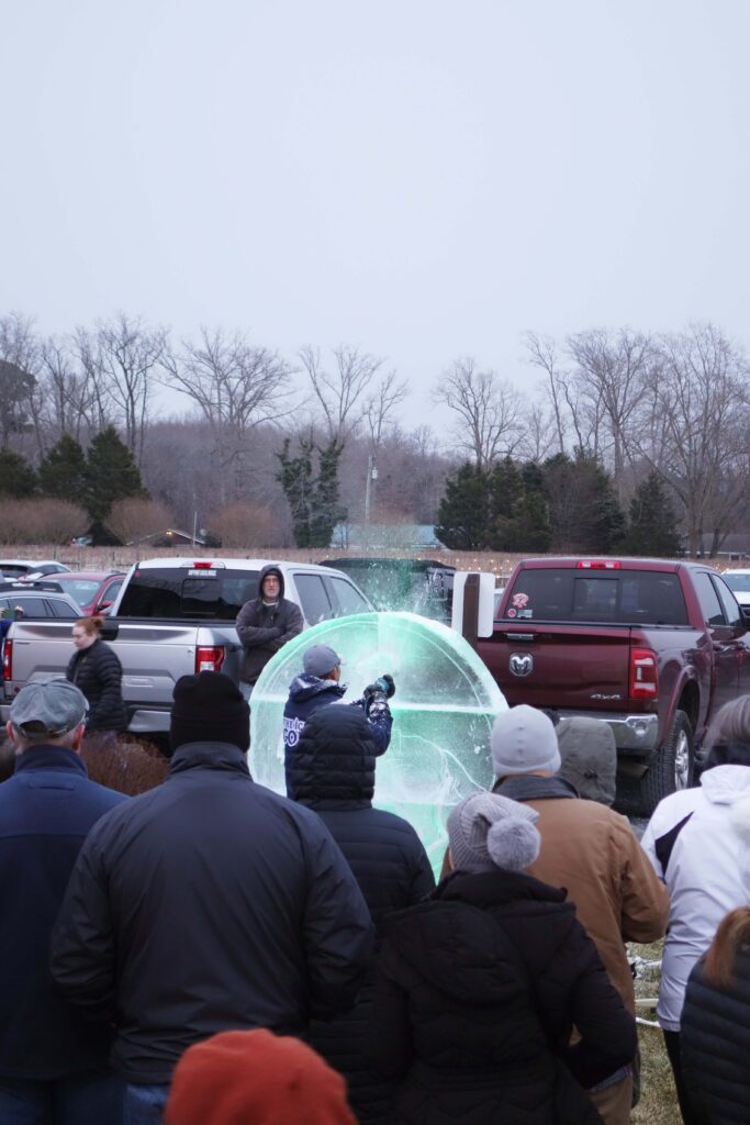 a crowd of people watching a man fly a kite