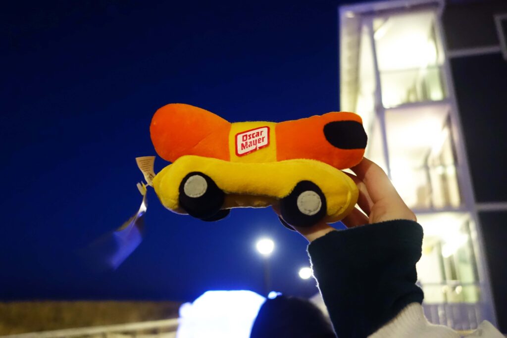 a person holding a yellow toy car in front of a building