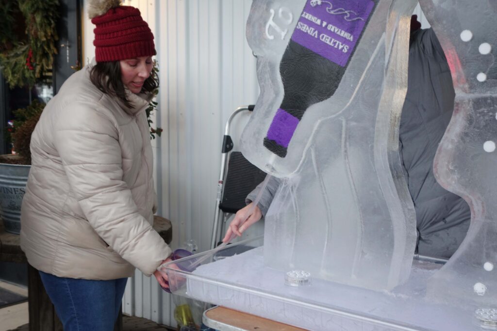 a woman opening a wine bottle in an ice sculpture