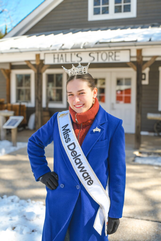 a woman wearing a blue coat and a crown