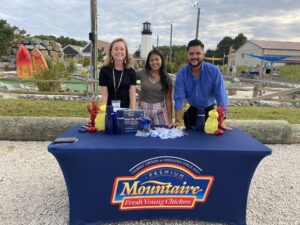 three people standing behind a blue table at a park