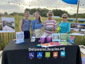 three women standing behind a table with books on it
