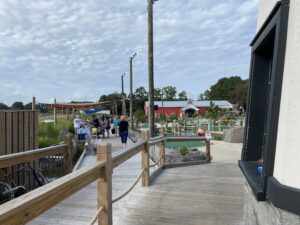 people walking on a wooden walkway over a river