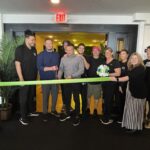 a group of people standing in front of a green ribbon