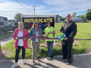 a group of people holding a ribbon in front of a sign