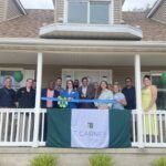 a group of people standing on a porch holding a ribbon