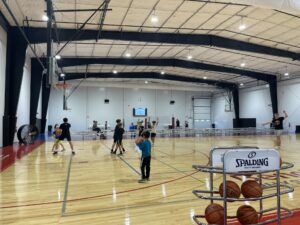 a group of people playing basketball inside of a gym