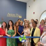 a group of women standing in front of a blue ribbon