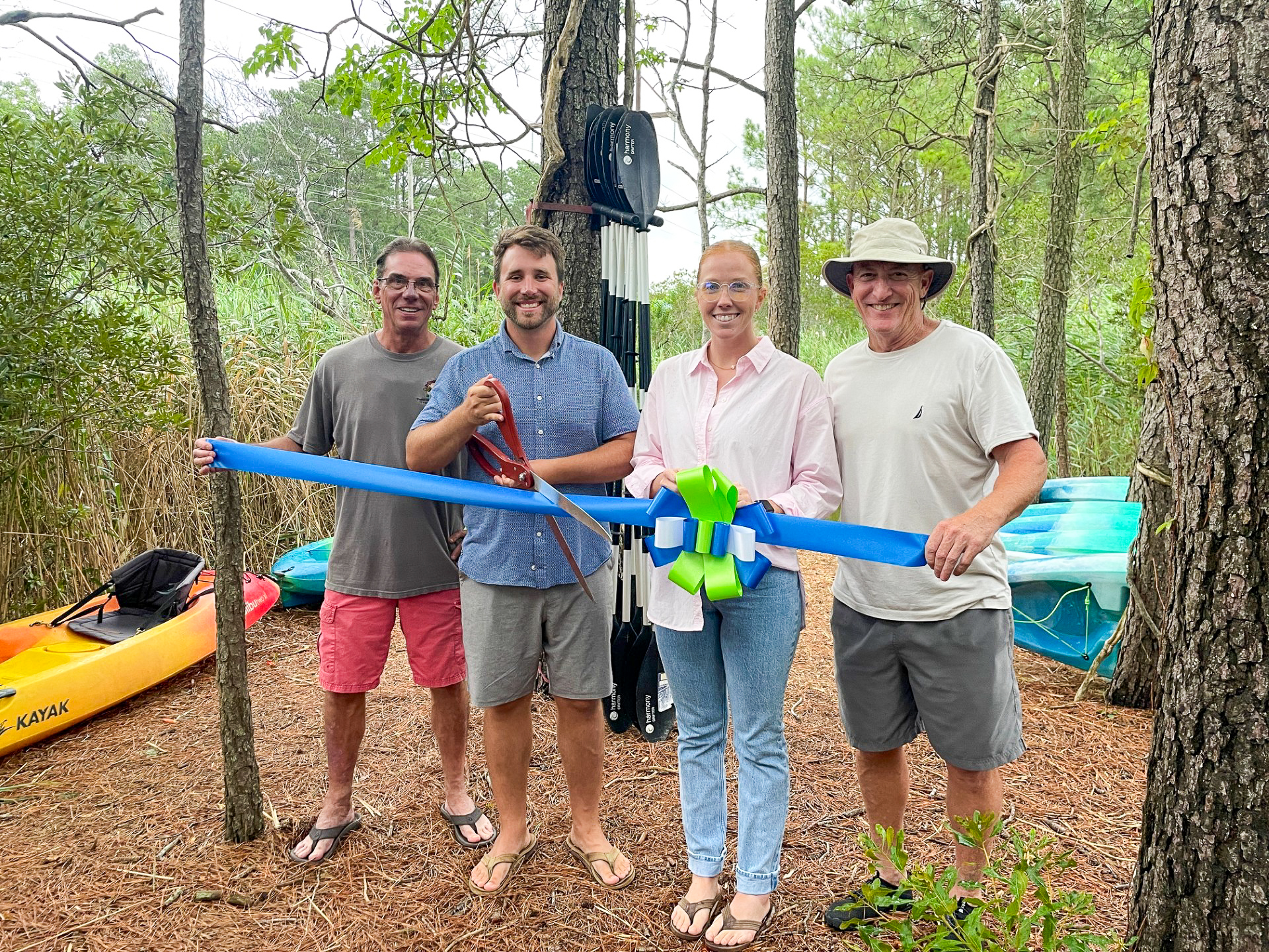 a group of people holding a blue ribbon in the woods