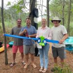 a group of people standing next to each other holding a blue ribbon