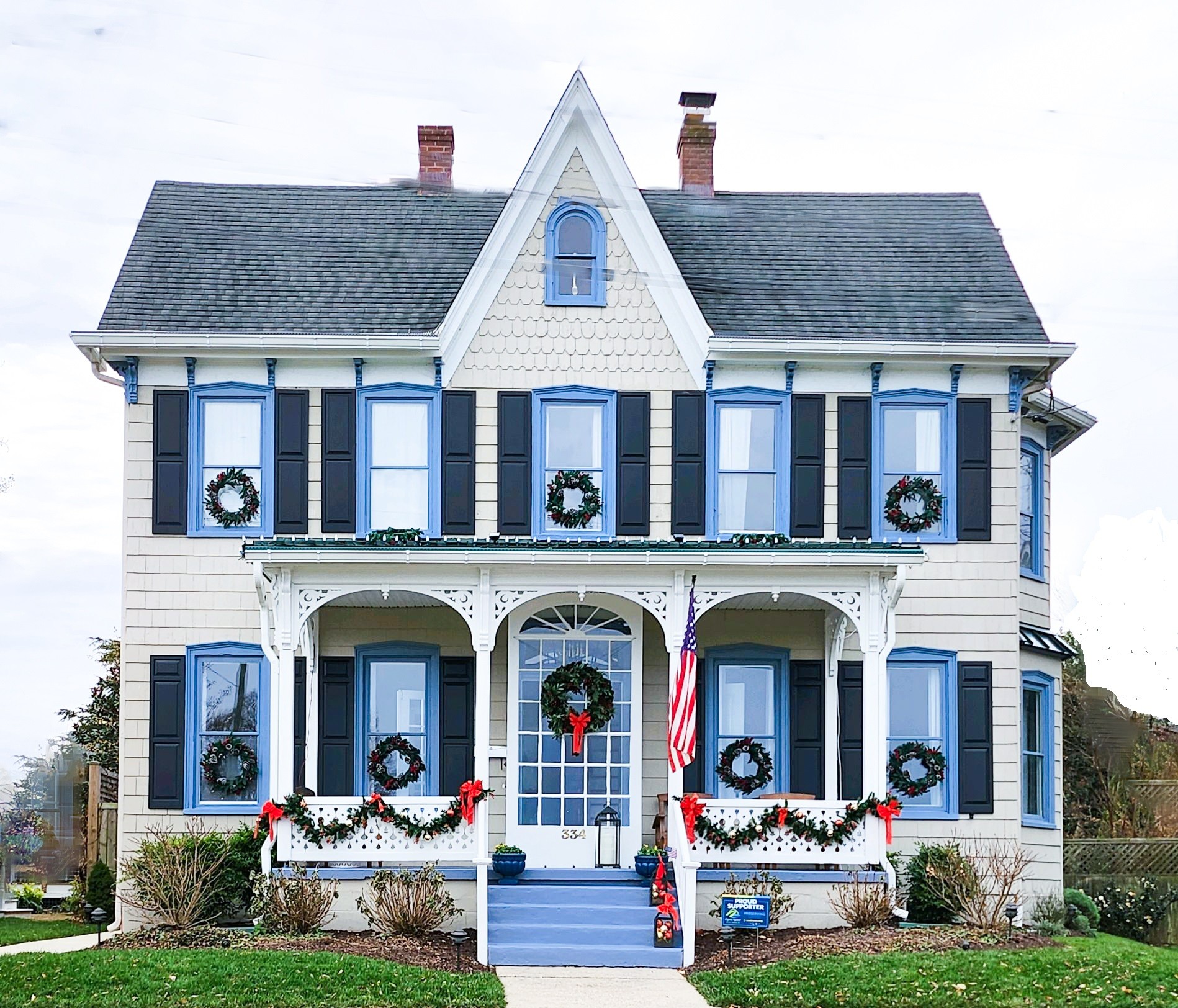 a white house with blue shutters and wreaths