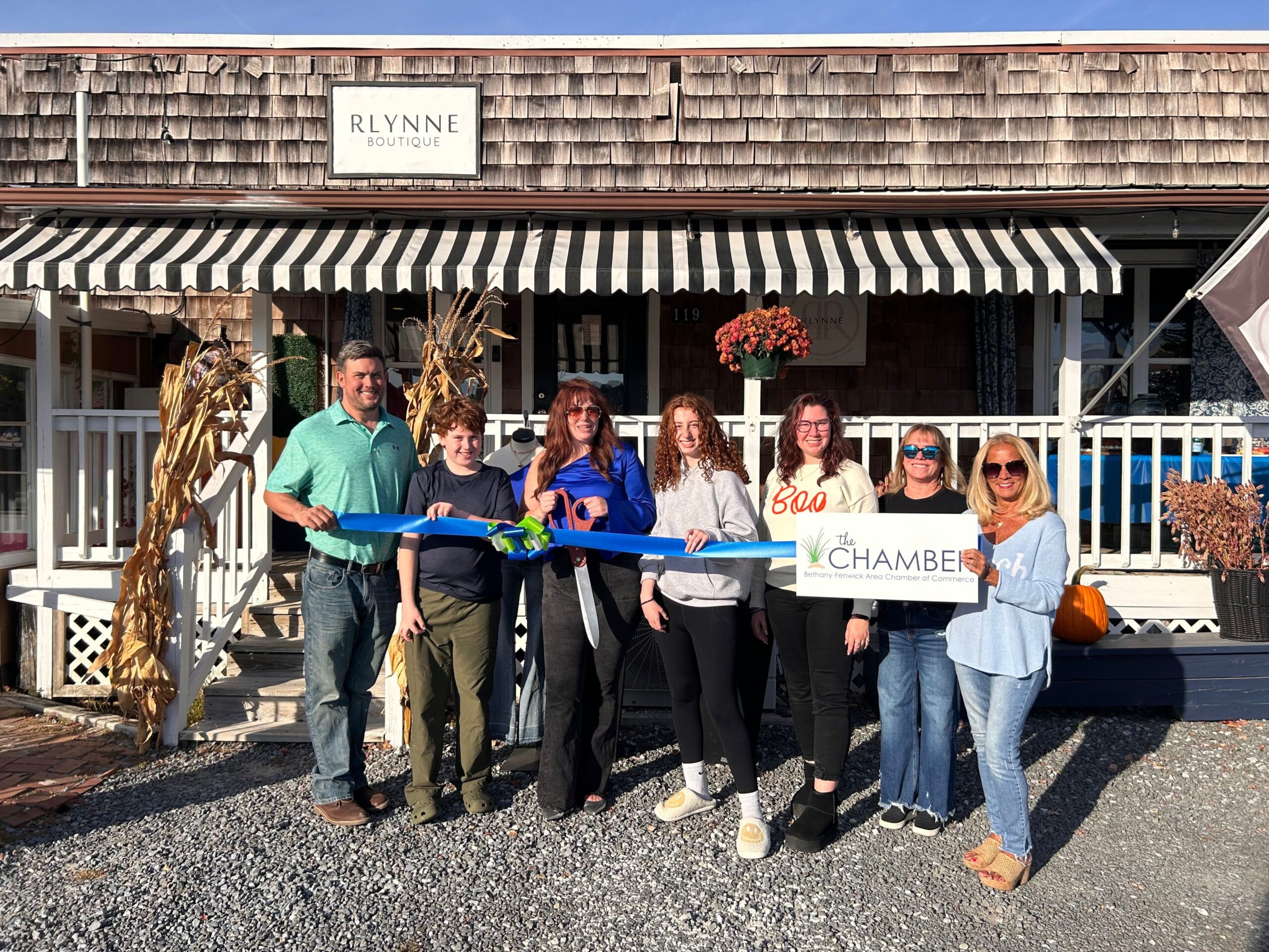 a group of people holding a ribbon in front of a store