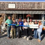 a group of people holding a ribbon in front of a store