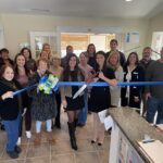 a group of people standing in a room holding a blue ribbon
