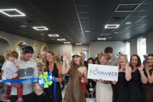 a group of people standing in a room holding a ribbon