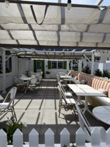 a patio with tables and chairs and a white fence