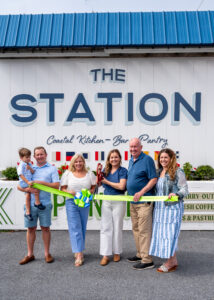 a group of people holding a ribbon in front of a building