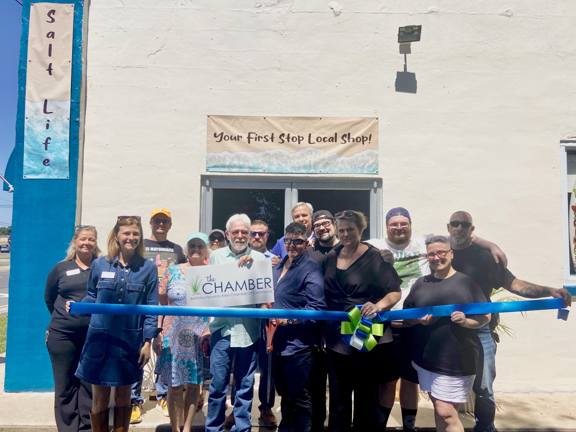 a group of people holding a ribbon in front of a building