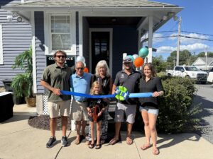 a group of people holding a ribbon in front of a house