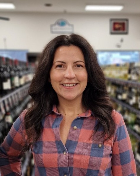 a woman standing in front of a row of wine bottles