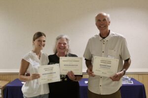 two women and a man holding up their diplomas