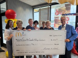 a group of people standing around a giant check