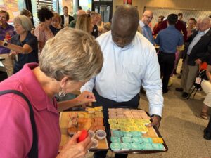 a group of people standing around a table with trays of food