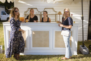a group of women standing around a white bar