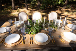 a wooden table topped with white plates and place settings