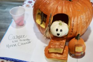 a pumpkin shaped like a house with a stuffed animal inside