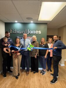 a group of people holding a blue ribbon in front of a wall