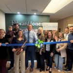 a group of people holding a blue ribbon in front of a wall