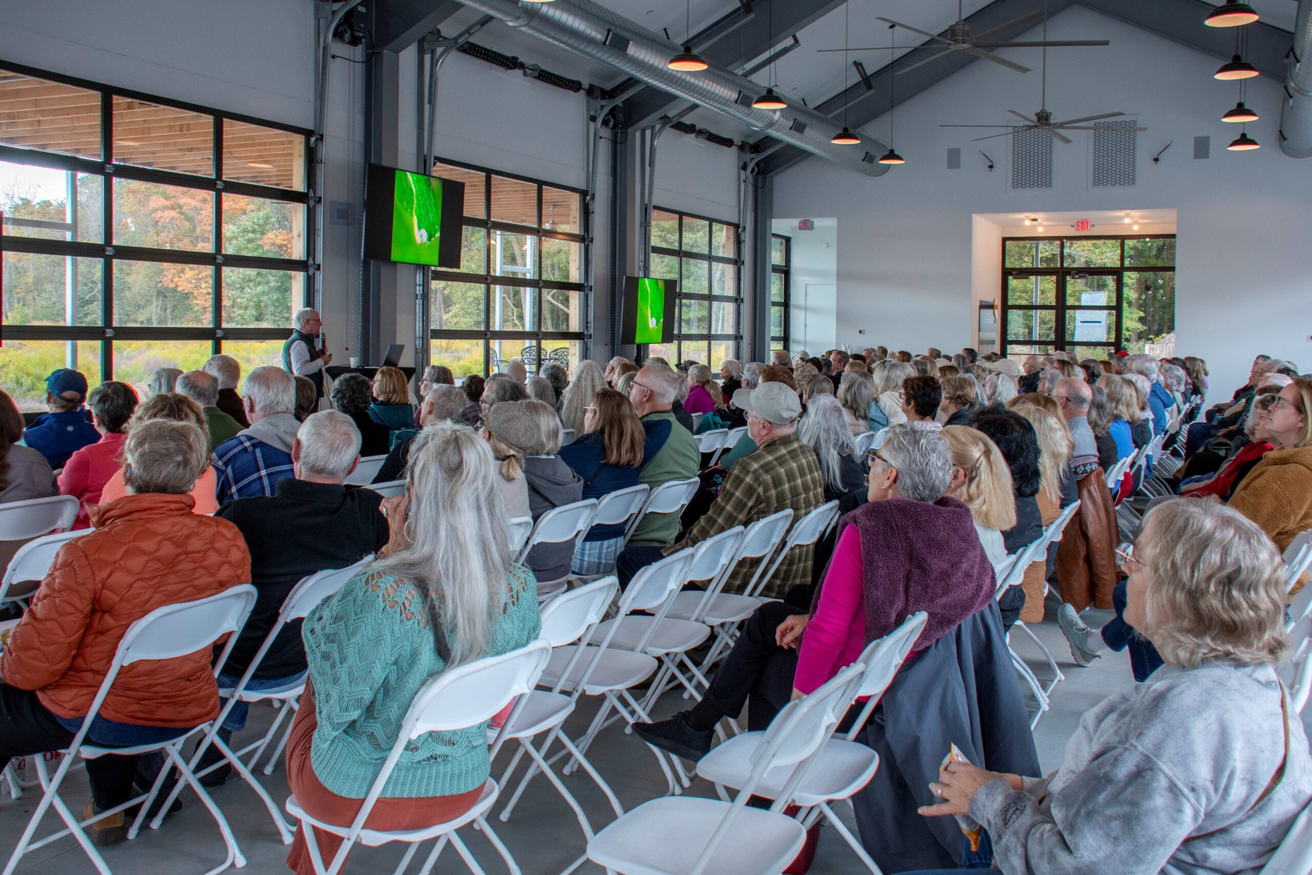 a large group of people sitting in chairs in a room