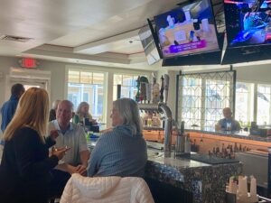 a group of people sitting at a bar watching tvs