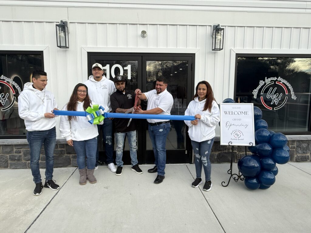 a group of people holding a ribbon in front of a building