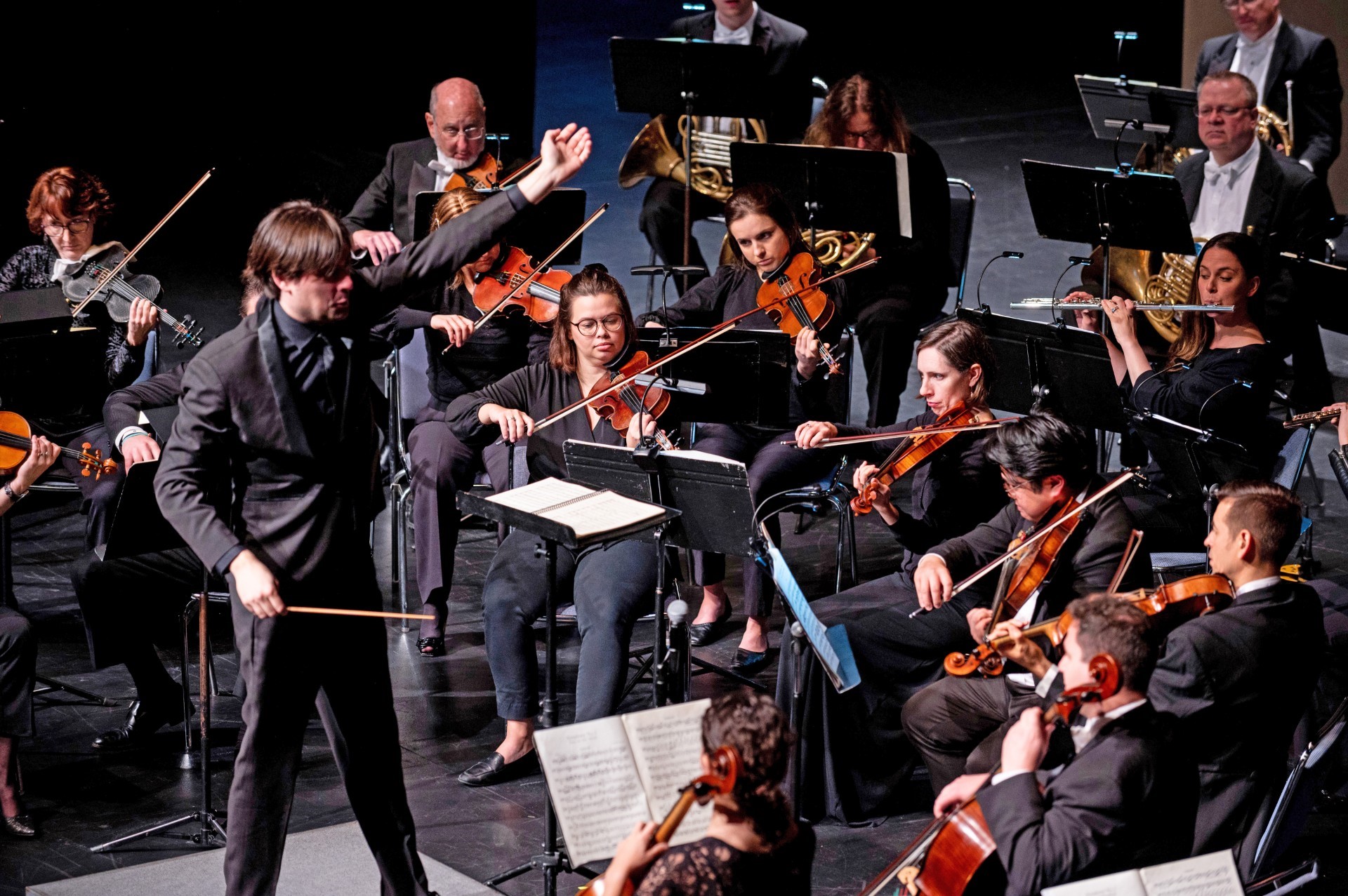 a conductor and orchestra performing on stage