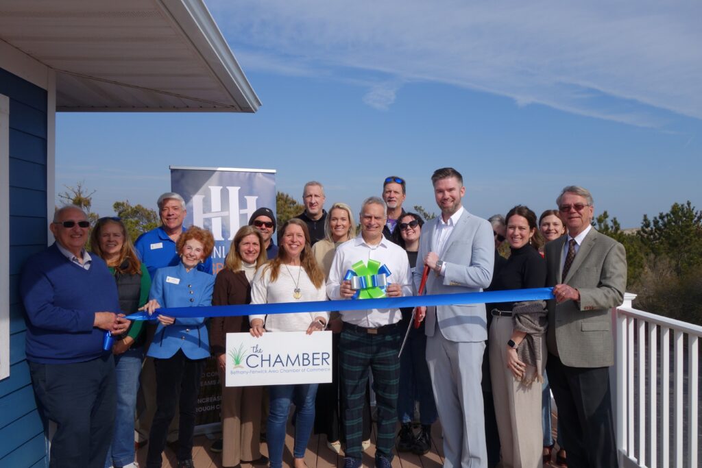 a group of people standing on a porch holding a ribbon