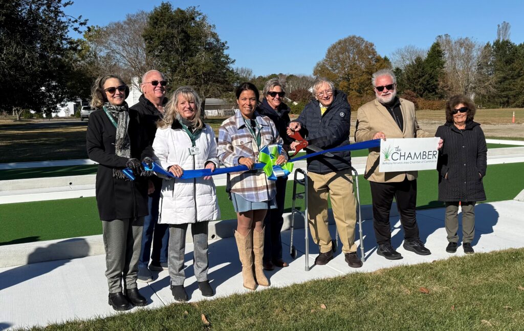 a group of people standing next to each other holding a ribbon
