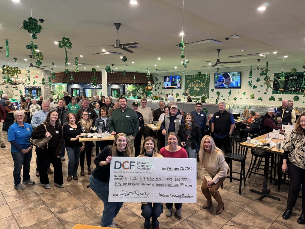 a group of people standing in a room holding a check