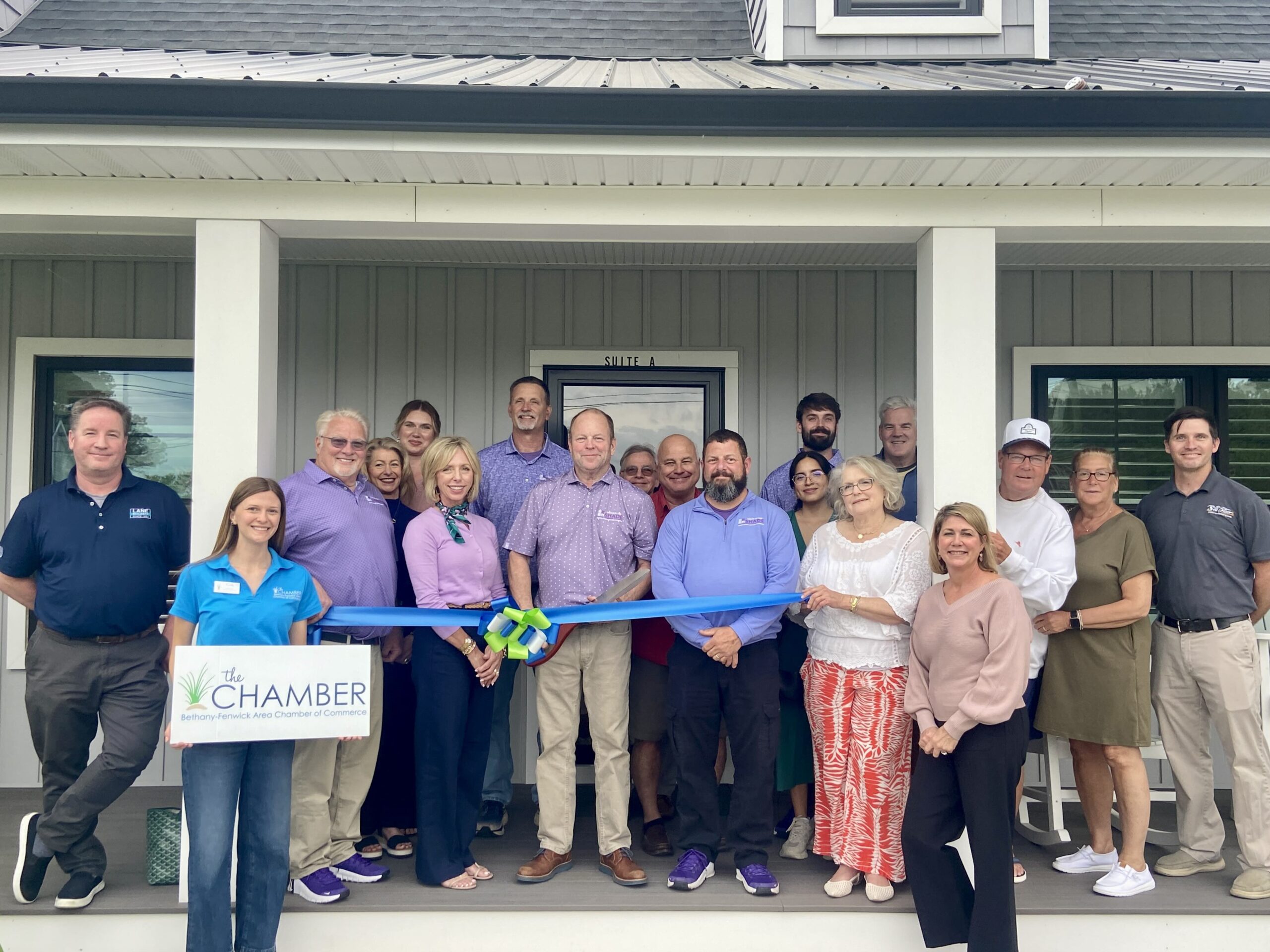 a group of people standing on a porch holding a ribbon