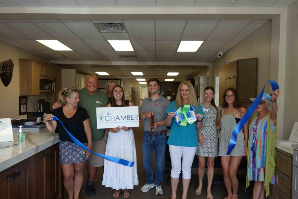 a group of people standing in a kitchen holding a ribbon