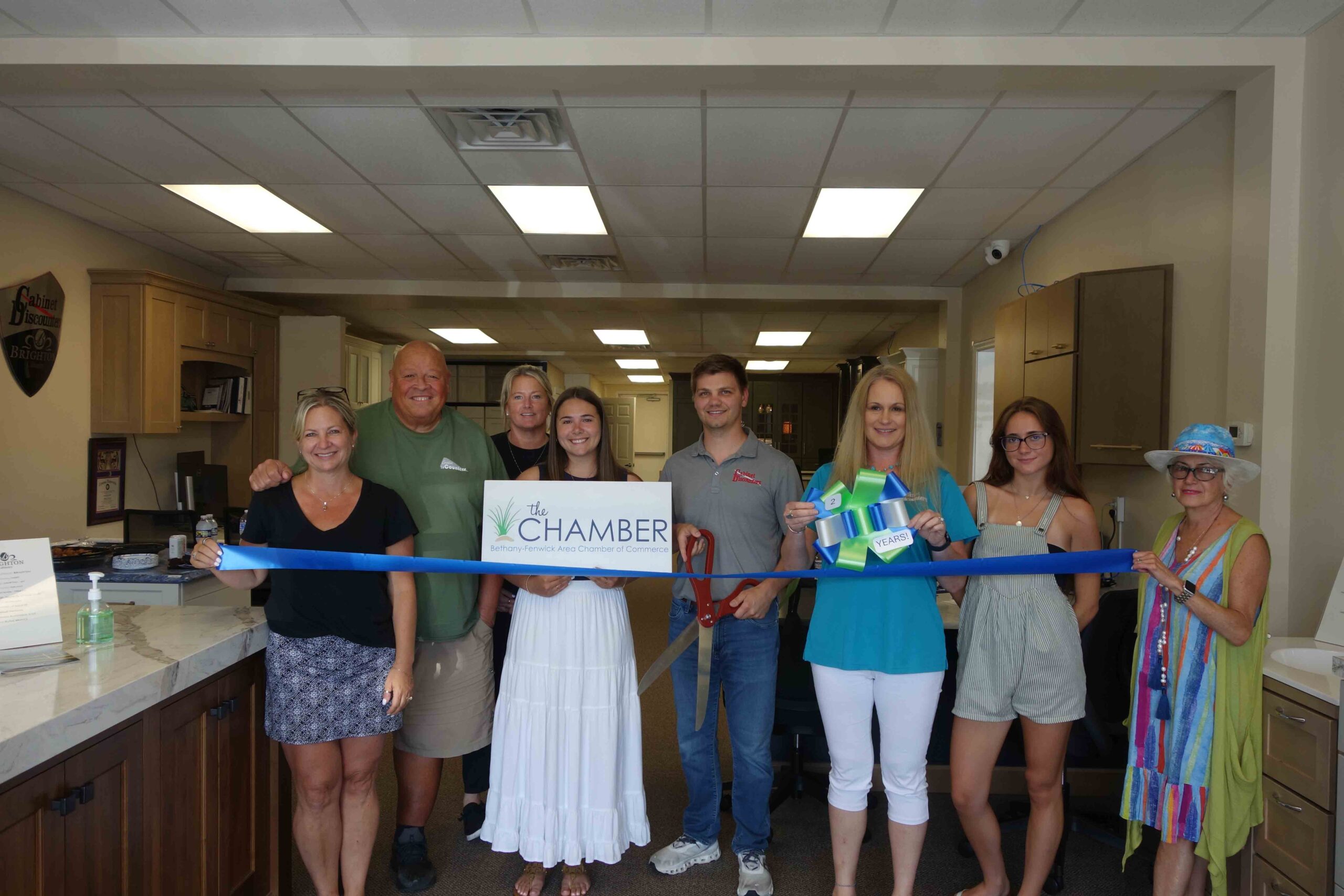 a group of people holding a ribbon in a kitchen