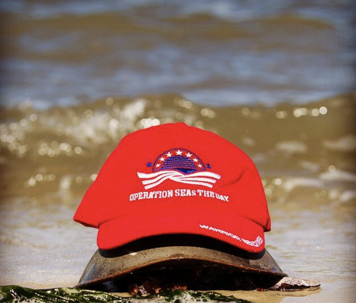 a red hat sitting on top of a surfboard in the ocean