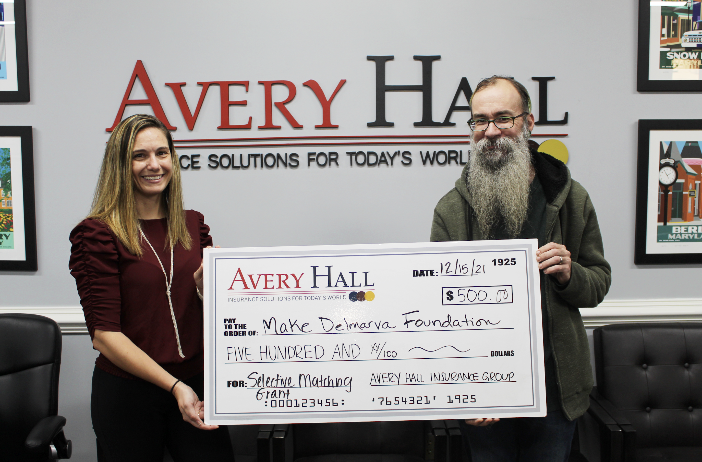 two people holding a large cheque in front of a wall