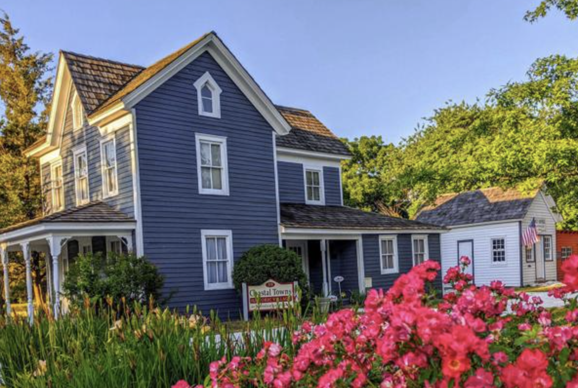 a blue house surrounded by flowers and trees