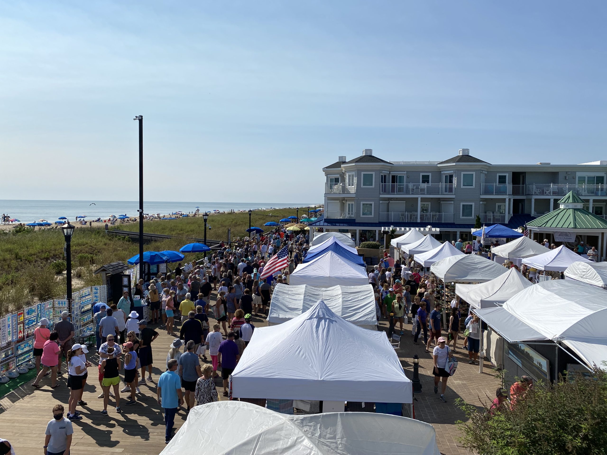 a crowd of people standing around tents on a beach