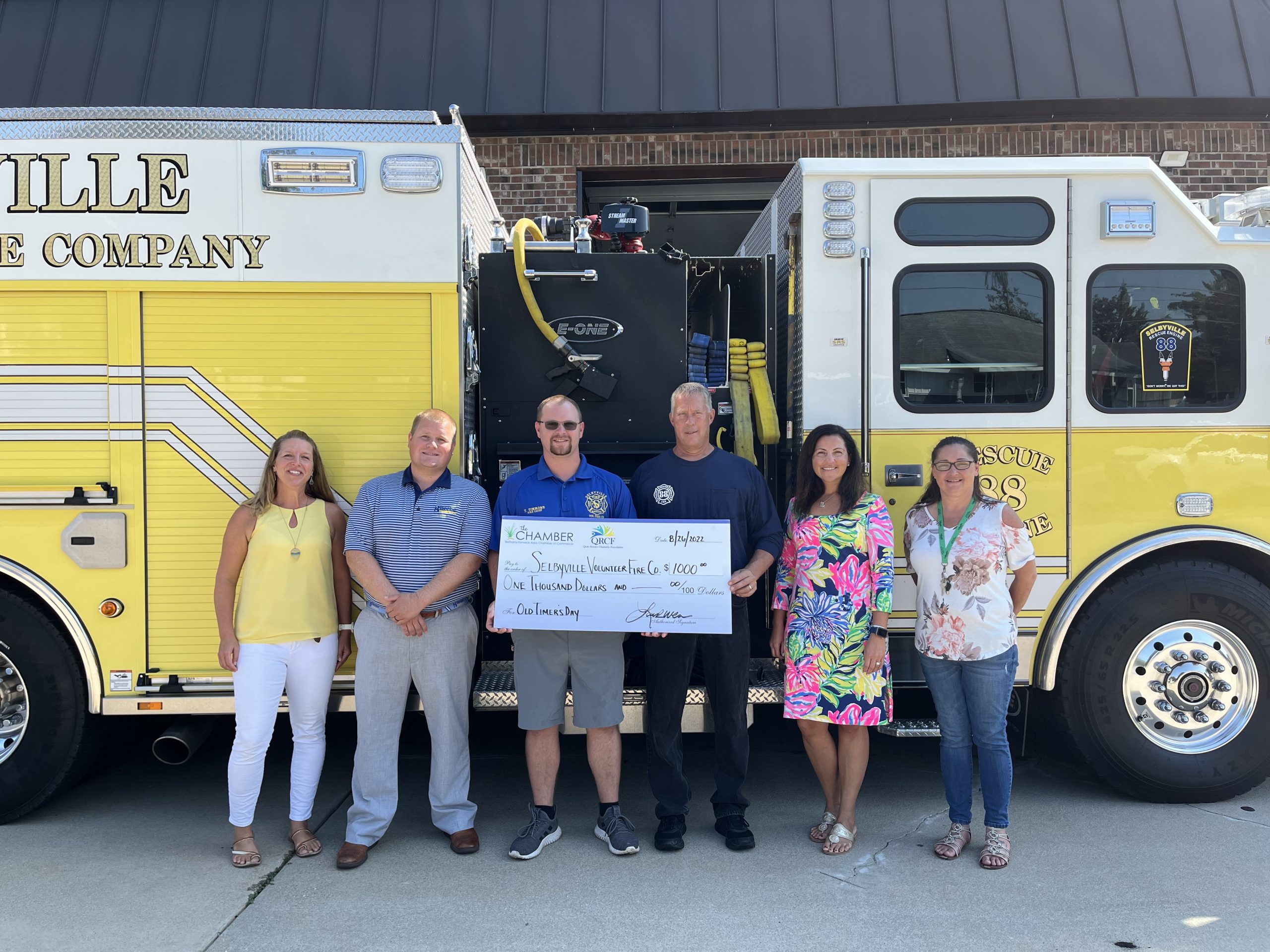 a group of people standing in front of a yellow fire truck