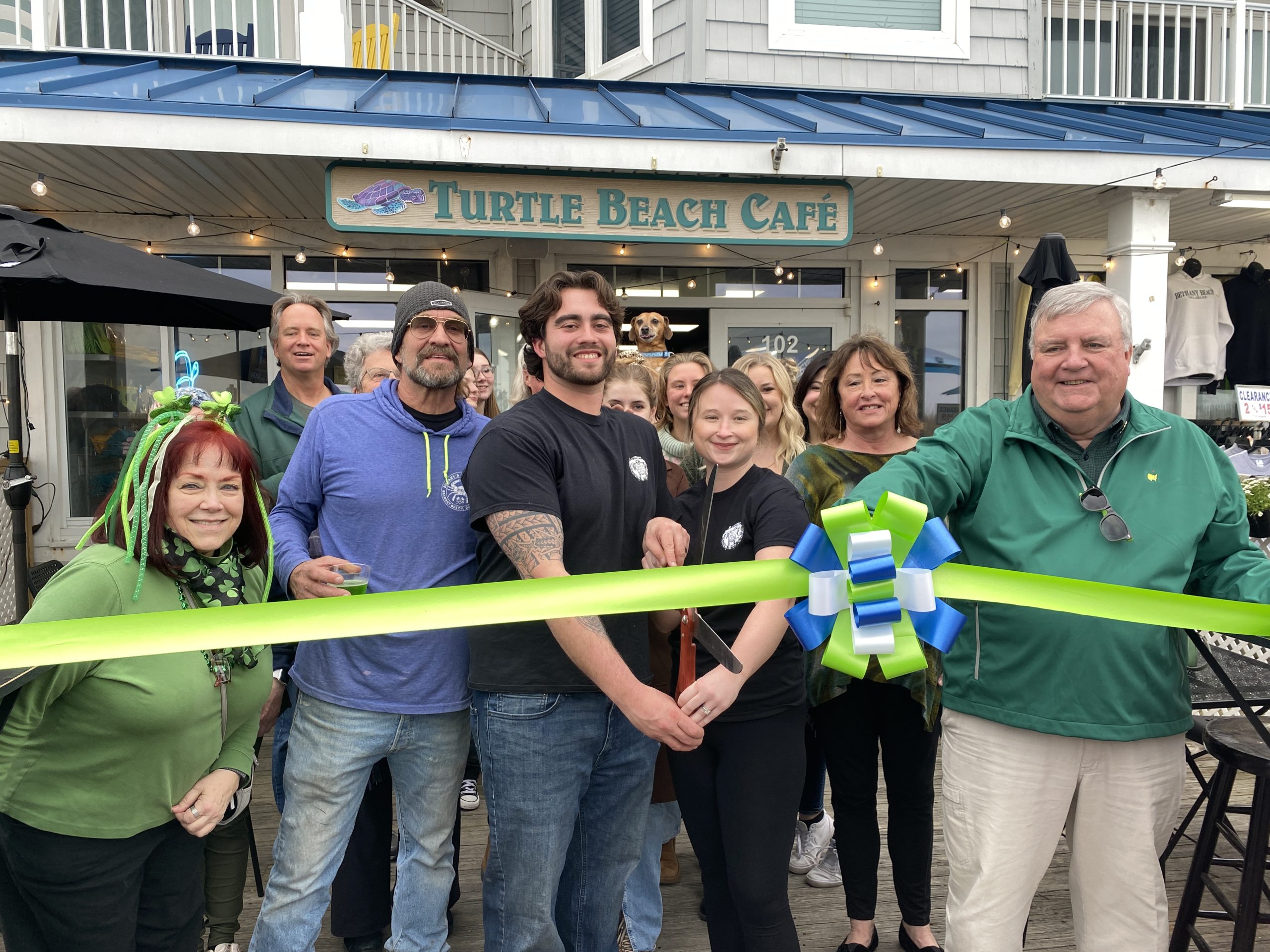 a group of people holding a ribbon in front of a restaurant