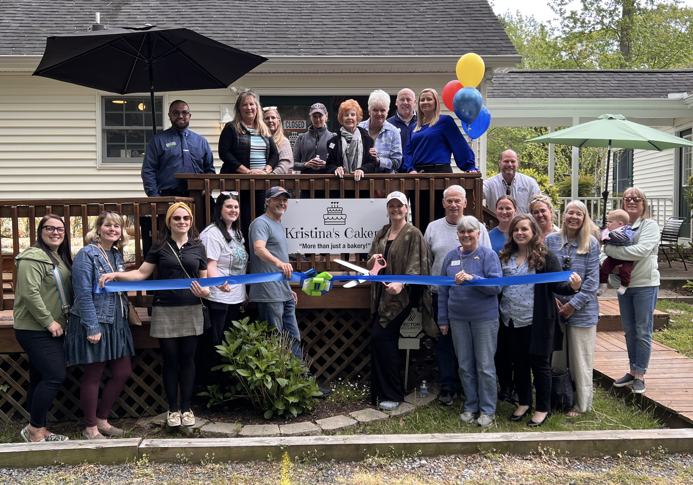 a group of people holding a ribbon in front of a house